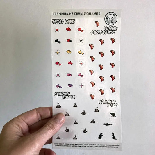 A hand holding one of Little Hunterman's Journal Sticker Sheet 02 up against a light background.