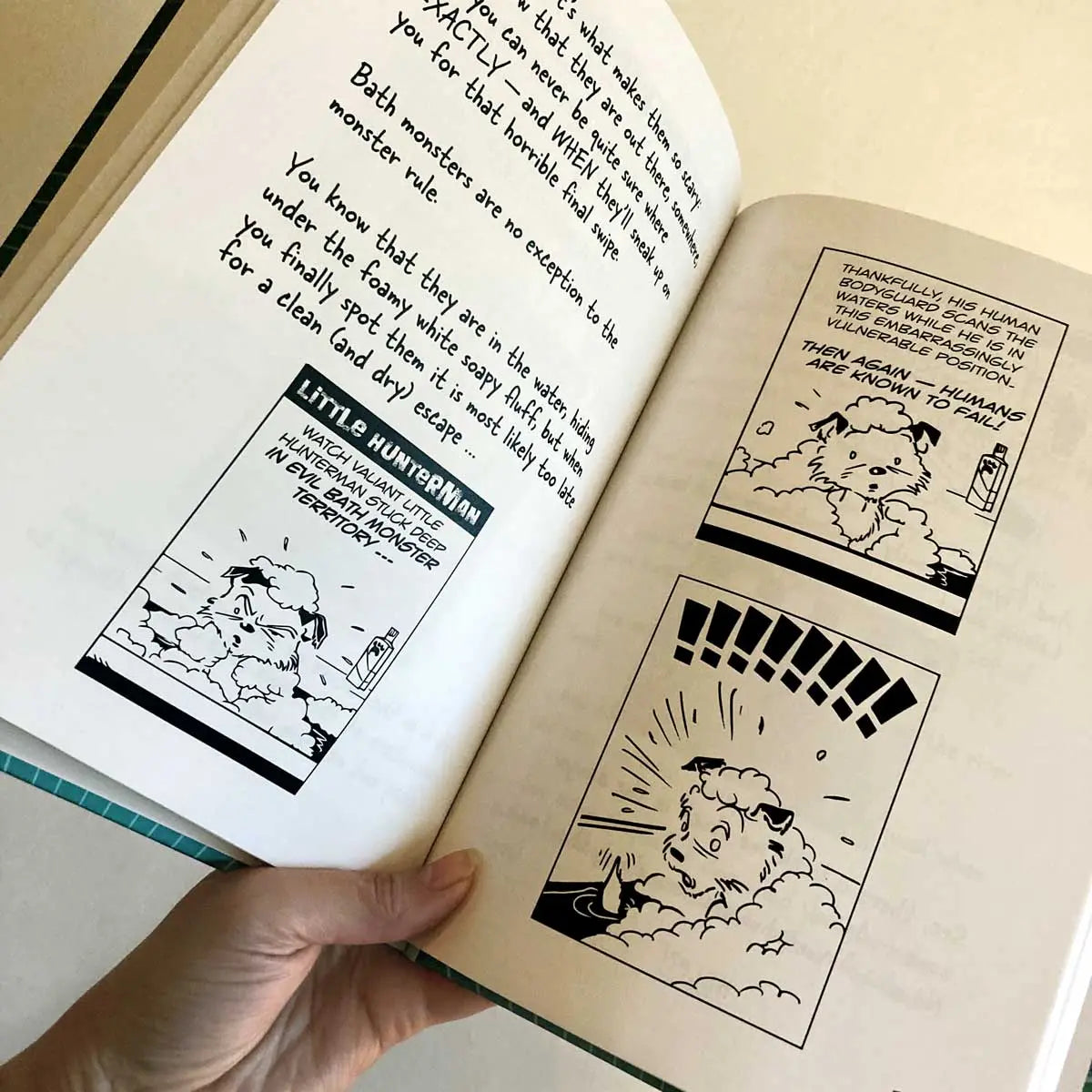 The Big World According to Little Hunterman by Hunter Lassal, premium edition hardcover with black and white illustrations on white, coated paper. This image shows a hand holding an open book against a light background, giving you an impression of the layout and illustration style.