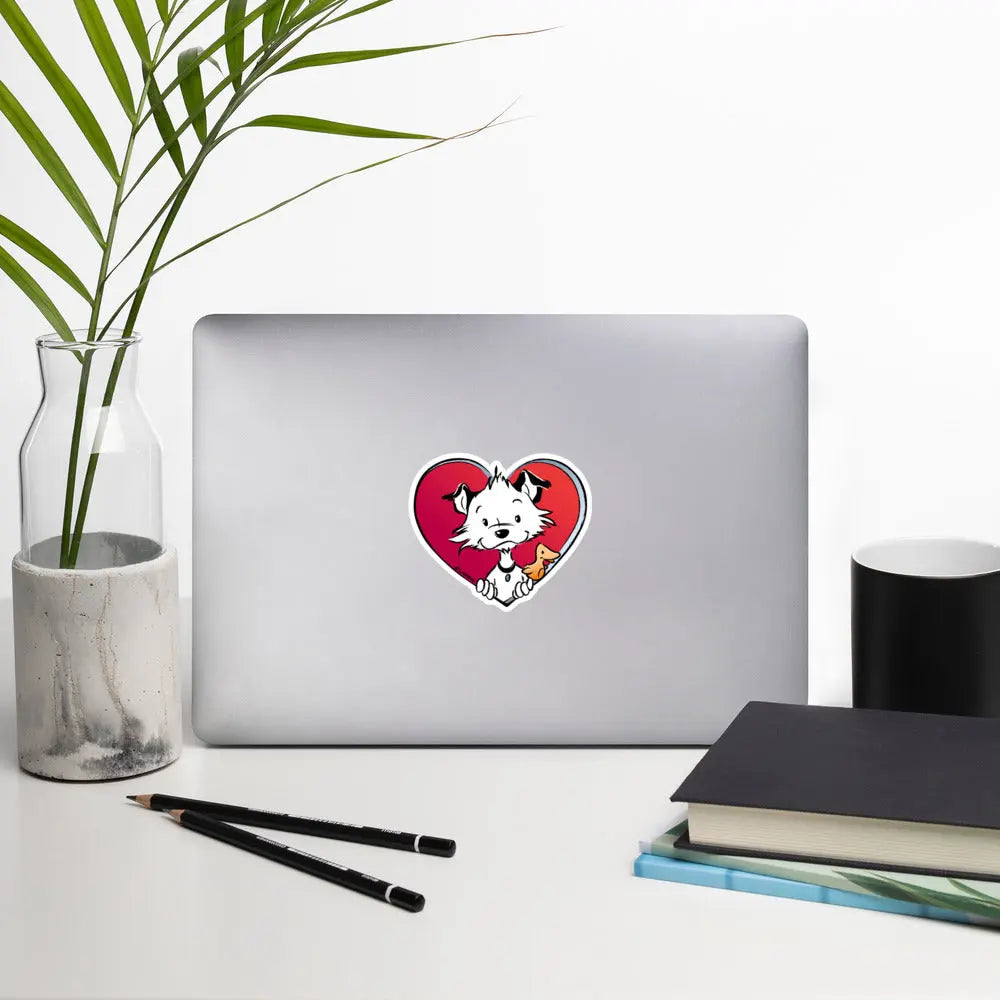 Image shows a desk-like situation with a notebook, a plant, books and pencils with one of Little Hunterman's "Sticky Doggie Love" stickers attached to the back of the open notebook lid.