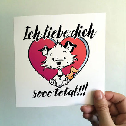 Front of square Little Hunterman card showing him and Flynn looking out of a big red heart with large text saying in German: Ich liebe dich sooo total!!!  With a hand holding the card agains a light background