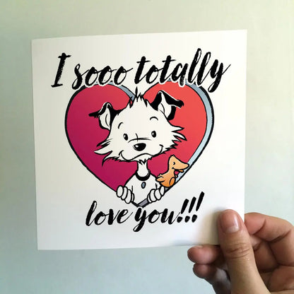 Image shows a square Little Hunterman card with him and Flynn looking out of a big red heart with large text saying: I sooo totally love you!!! With a hand holding the card agains a light background