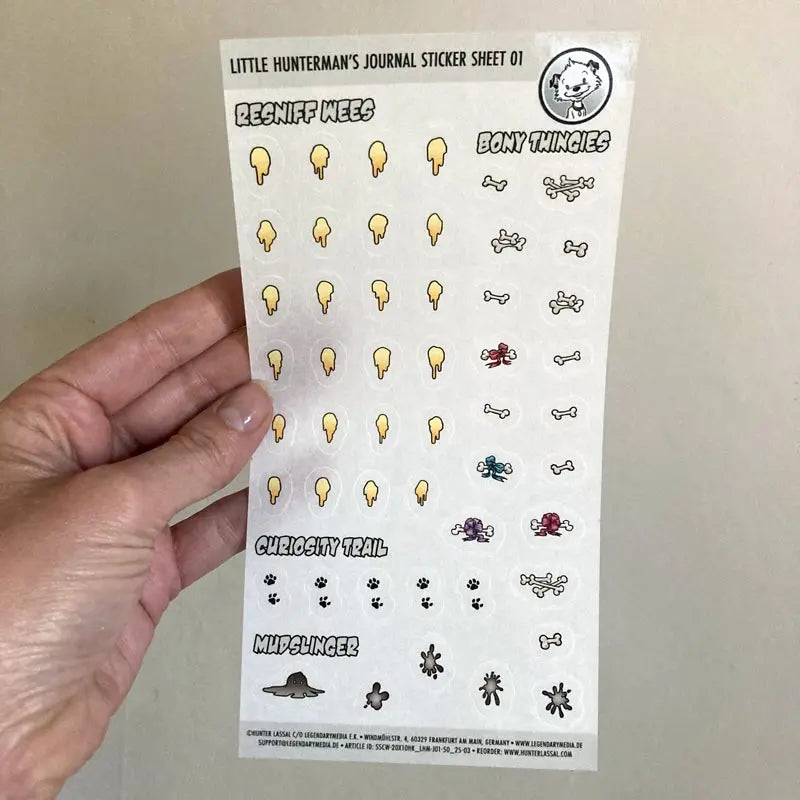 A hand holding one of Little Hunterman's Journal Sticker Sheet 01 up against a light background.