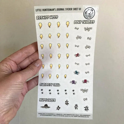 A hand holding one of Little Hunterman's Journal Sticker Sheet 01 up against a light background.
