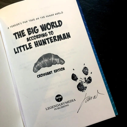 The Big World According to Little Hunterman, retailer version hardcover with black and white illustrations and creme colored paper. The image shows the signed (by the human) and paw-grammed (by the dog) title page.