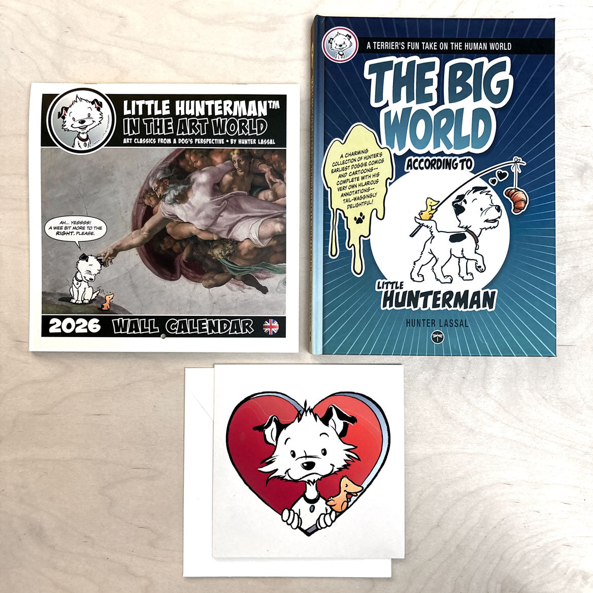 A calendar, a book, and a large card featuring a cartoon dog character on a light wooden surface